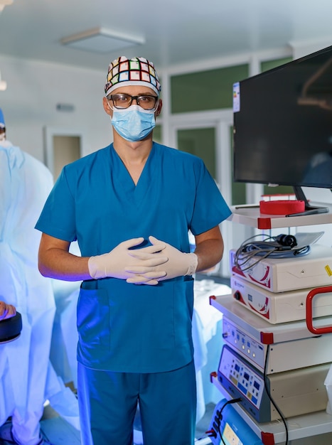 Pracownik medyczny. Poważny człowiek stojący na sali operacyjnej. Noszenie munduru i stanie w sali operacyjnej. Praca w szpitalu