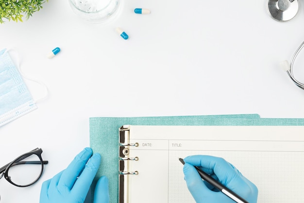 Pracownik medyczny przy stole pisze w widoku z góry notebooka