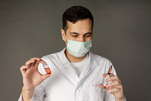 pracownik medyczny trzyma szczepionkę i nosi maskę chroniącą przed koronawirusem