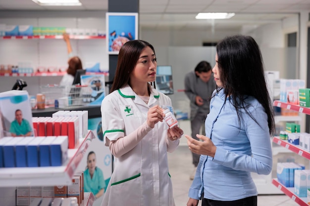 Pracownik medyczny udzielający pomocy klientowi azjatyckiemu, mówiący o medycynie w pudełkach i produktach farmaceutycznych. Farmaceuta pomaga klientowi z lekami i suplementami opieki zdrowotnej.