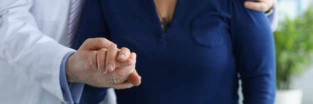 Pracownik medyczny w mundurze pomaga starszej kobiecie chodzić trzymając się za rękę