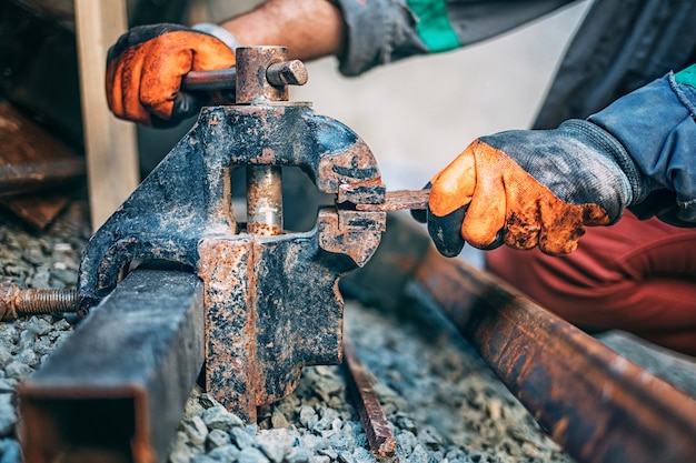 Pracownik mocuje metalową część w imadle przed cięciem, zbliżenie