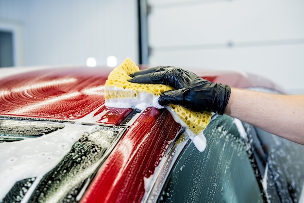 Pracownik Myjący Czerwony Samochód Gąbką Na Myjni Samochodowej