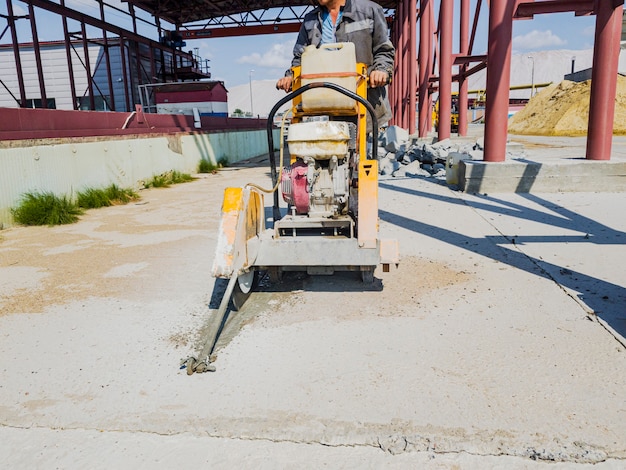 Pracownik na budowie tnie beton diamentową piłą. Łamacz betonu