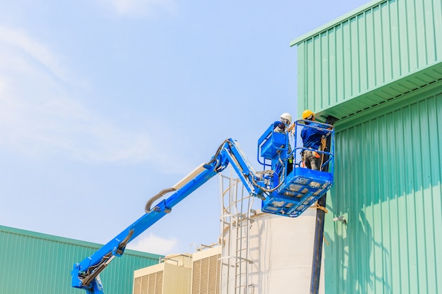 Pracownik na hydraulicznym podnośniku Podnośnik na platformie w kierunku dachu fabryki