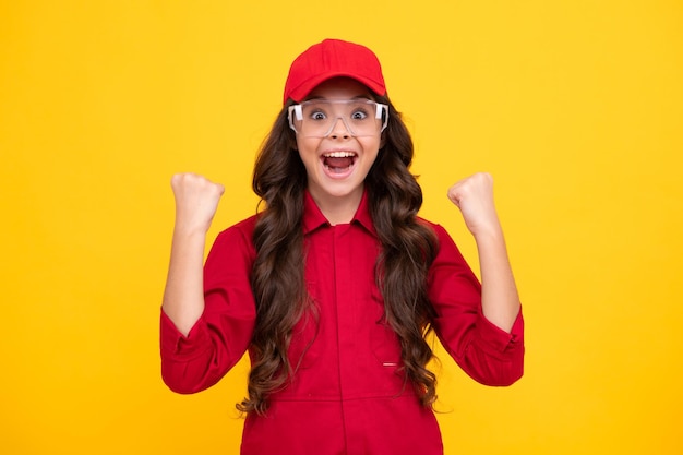 Pracownik nastolatek dziecko ubrany w kombinezon czerwoną czapkę i okulary ochronne Studio strzał portret na białym tle Podekscytowana nastolatka