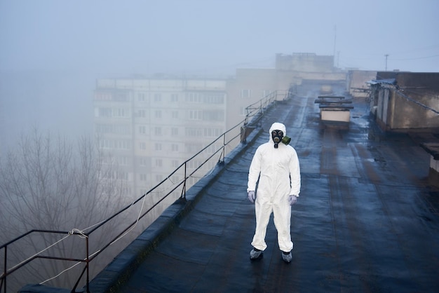 Zdjęcie pracownik naukowy w kombinezonie ochronnym i masce przeciwgazowej przeprowadzający testy ekologiczne na dachu