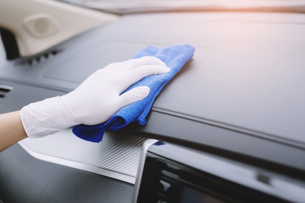 Pracownik nosić rękawice do czyszczenia konsoli samochodowej z ściereczką z mikrofibry, koncepcja szczegółowej myjni samochodowej.