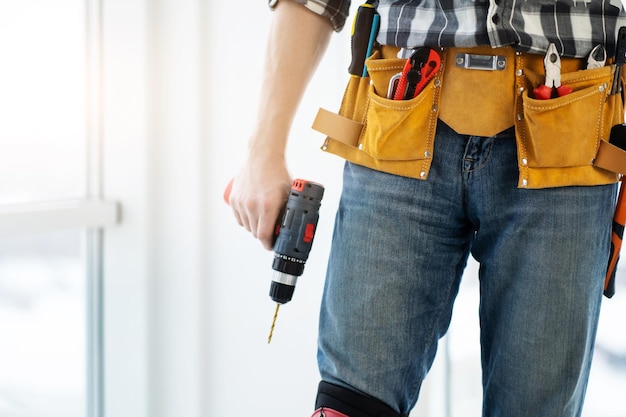 Zdjęcie pracownik noszący pasek narzędziowy i trzymający wiertło