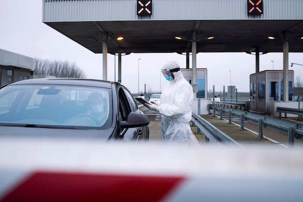 Pracownik Opieki Zdrowotnej W Białym Kombinezonie Ochronnym Kontrolujący Pasażerów I Test Pcr Na Przejściu Granicznym Z Powodu Globalnej Pandemii Koronawirusa.