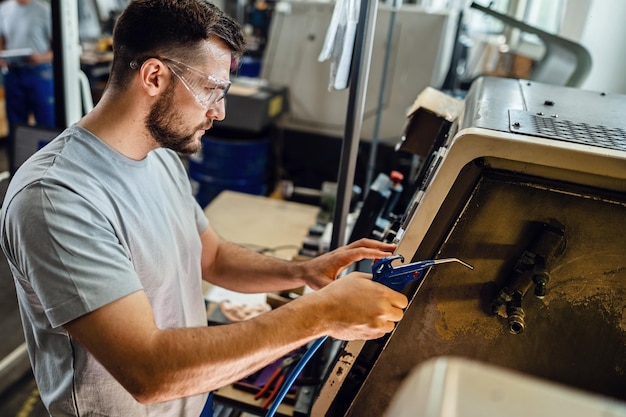 Pracownik przemysłowy obsługujący maszynę CNC na linii produkcyjnej