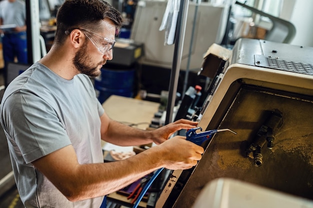 Zdjęcie pracownik przemysłowy obsługujący maszynę cnc na linii produkcyjnej