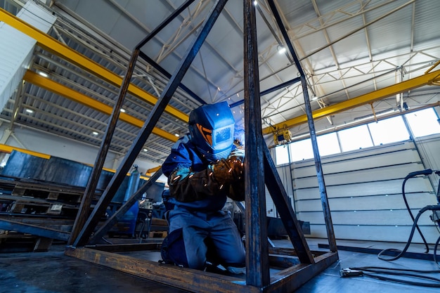 Pracownik przemysłowy w masce bezpieczeństwa Spawacz pracujący z metalową konstrukcją