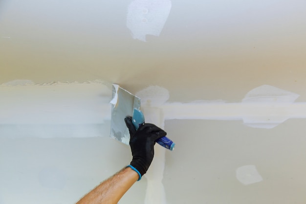 Zdjęcie pracownik puttied ściana używa farby szpachelkę