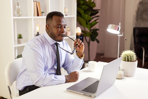 Pracownik rozciągający się przy biurku w pracy zmęczony pracownik biurowy Afroamerykanów