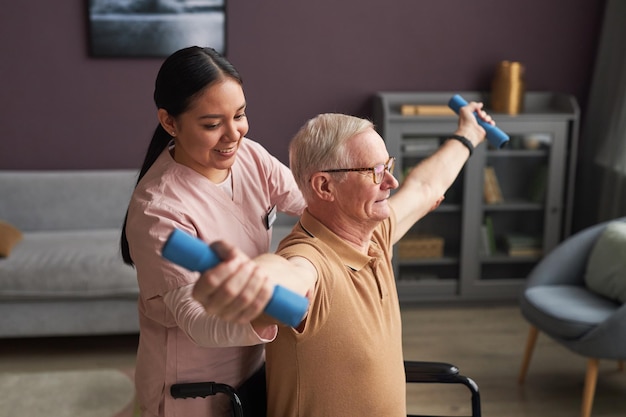 Pracownik socjalny pomaga starszemu mężczyźnie ćwiczyć
