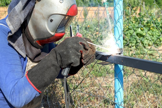 Pracownik spawa metalowe rury za pomocą spawania elektrodowego na zewnątrz