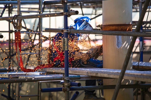 Pracownik używający elektrycznego szlifowania iskrowego na rurze ze stali węglowej spawacza wewnątrz zbiornika;