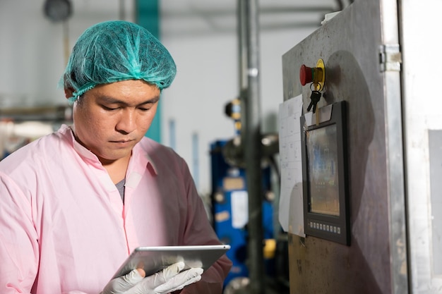 Pracownik używający tabletu w fabryce napojów nadzoruje napełnianie wody gazowanej