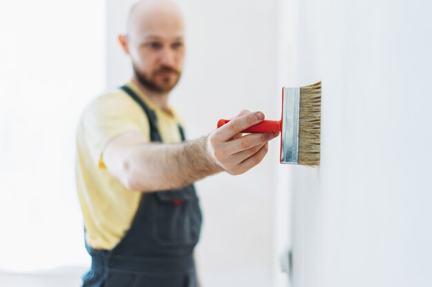 Zdjęcie pracownik w kombinezonie naprawia przyklejanie ścian pod tapetą lub podkładem na ścianę