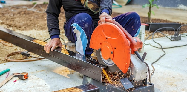 pracownik w ubraniu roboczym używa elektrycznej noża do stali Cięcie dużych stalowych prętów