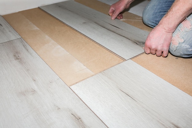 Zdjęcie pracownik wykonujący podłogi laminowane w mieszkaniu konserwacja naprawa renowacja drewniane deski parkietowe w pomieszczeniach