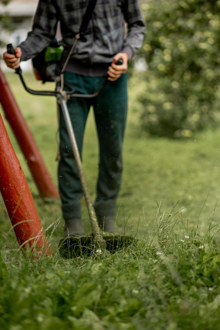 Zdjęcie pracownik z kosiarką gazową w rękach koszący trawę przed domem podkaszarka w rękach mężczyzny ogrodnik koszący trawę styl życia