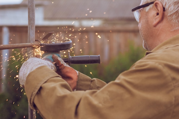 Pracownik za pomocą szlifierki tnie metalową konstrukcję