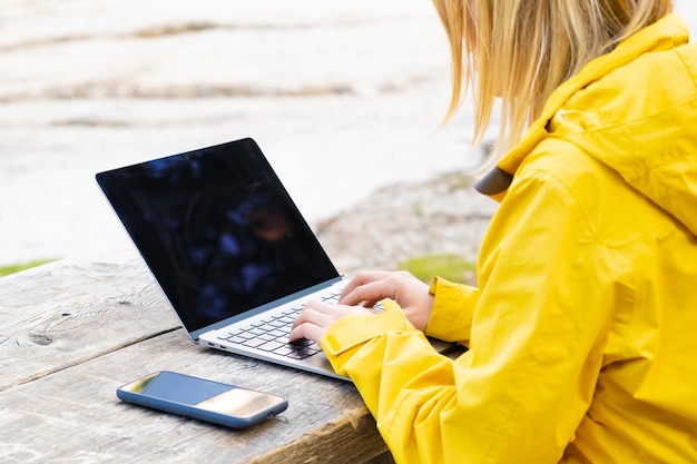 Pracownik zdalny relaksujący się w pobliżu jeziora i korzystający z laptopa