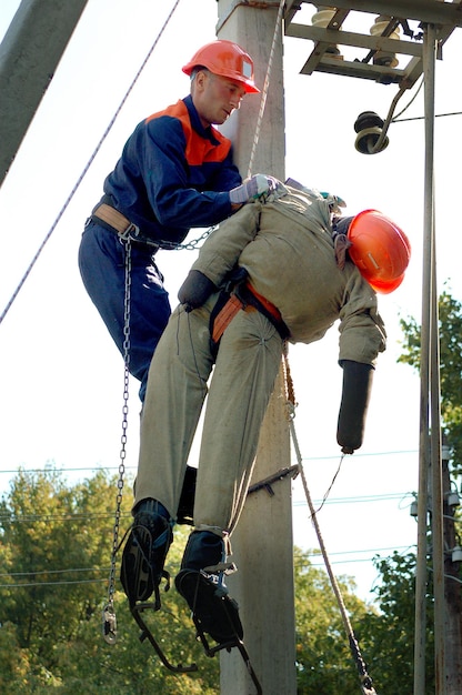 Pracownikowi dotkniętemu porażeniem prądem pomaga elektryk. Trening na manekinie.