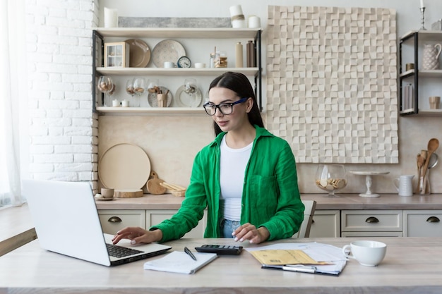 Pracuj zdalnie młoda piękna bizneswoman pracuje w domu, siedząc w domu, pracując w kuchni