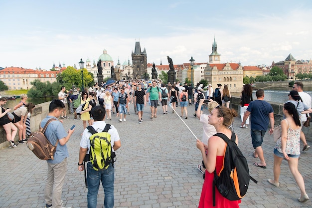 Praga, Republika Czeska - 03 czerwca 2017 r.: ludzie na moście Karola nad Wełtawą z posągami, wieżami, domami na błękitnym niebie. Cel turystyczny, podróże, wanderlust, koncepcja wakacji