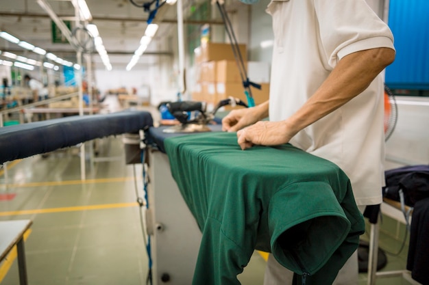 Pralnia prasuje kurtkę za pomocą Przemysłowej maszyny do prasowania Ujęcie zrobione w fabryce Fabryka tkanin włókienniczych proces roboczy wyposażenie pracowników krawieckich