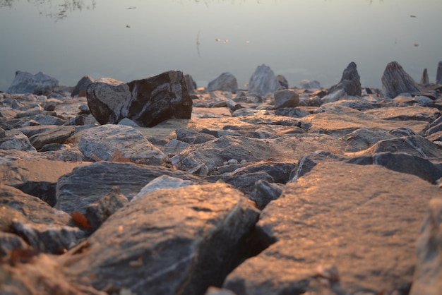 Prawdziwy naturalny surowy obraz bez edytowanego odbicia zachodu słońca na skałach i wodzie