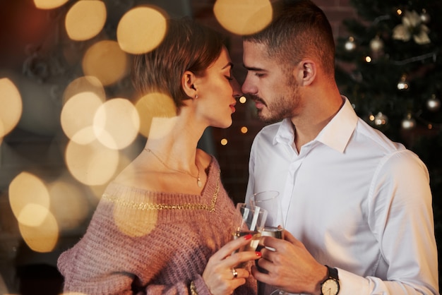 Prawie pocałunek. Miła para świętuje nowy rok w pomieszczeniu z klasycznymi pięknymi ubraniami