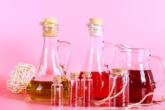 Zdjęcie pręciki szafranowe w małych słoiczkach i napoje z pręcikami szafranowymi na różowym tle