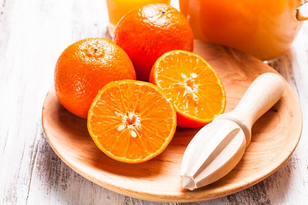 Preparat na sok mandarynkowy na śniadanie. Drewniany rozwiertak do cytrusów z owocami.