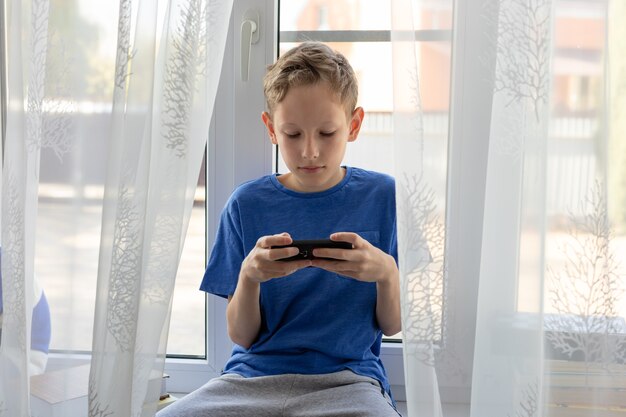 Preteen boy używa telefonu komórkowego, bawi się, używa aplikacji