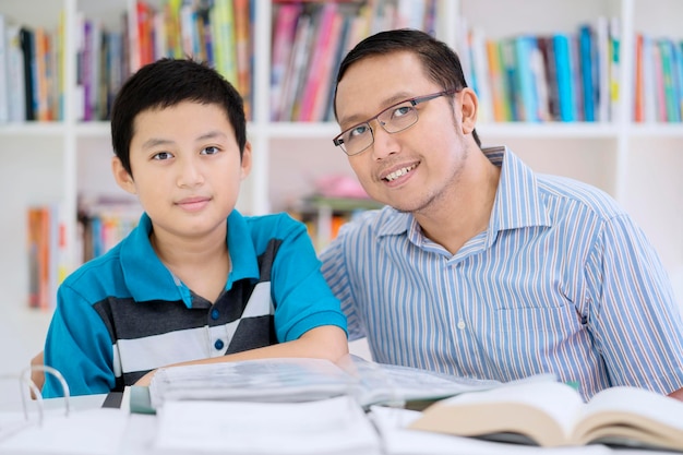 Preteen chłopiec uczeń ze swoim nauczycielem w bibliotece