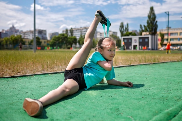 Preteen dziewczyna robi ćwiczenia z taśmą oporową fitness na publicznym boisku sportowym w sporcie miejskim