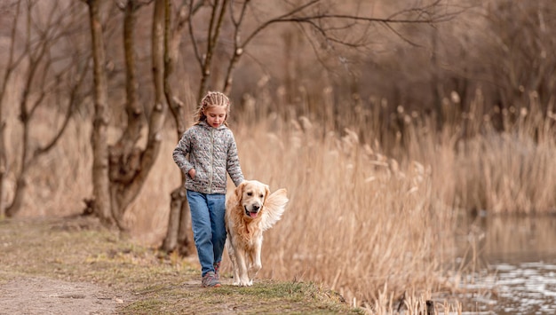 Preteen Dziewczyna Spacerująca Z Psem Golden Retriever W Pobliżu Rzeki W Okresie Wiosennym