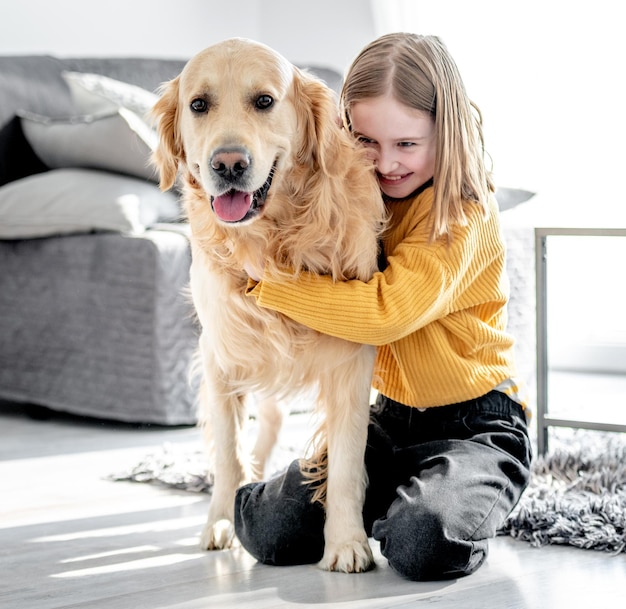 Preteen dziewczyna z golden retriever pies siedzi na podłodze i pieści pieska Ładne dziecko dziecko z labradorem w domu