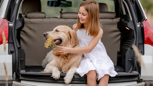 Preteen dziewczyna z psem golden retriever w bagażniku samochodu