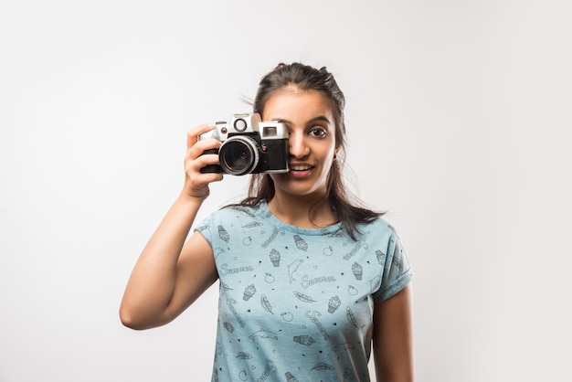 Pretty Indian azjatyckich dziewczyna z Retro Camera, stojąc na białym tle nad białym tłem. trzymanie lub klikanie zdjęć