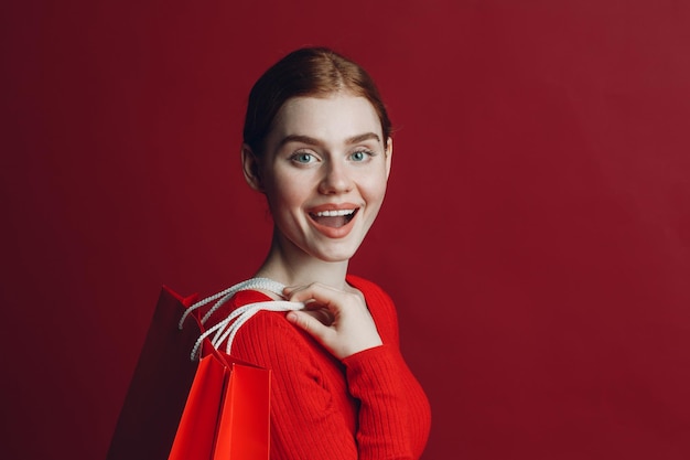 Pretty woman smilng portret z papierowymi czerwonymi torbami na zakupy Czarny piątek i koncepcja sprzedaży