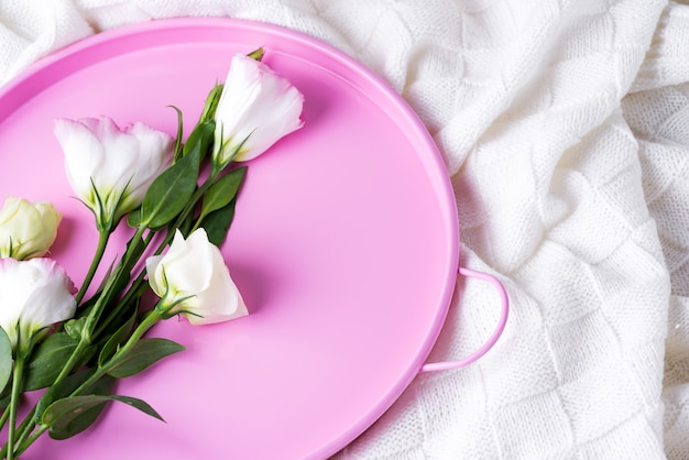 Prezent eustoma z pastelowych kwiatów na Walentynki lub Dzień Matki na różowej tacy na łóżku