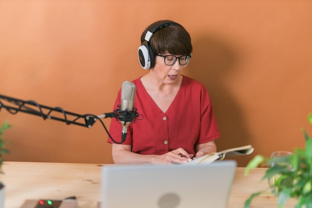 Zdjęcie prezenterka radiowa w średnim wieku rozmawiająca do mikrofonu i czytająca audycję radiową w internecie
