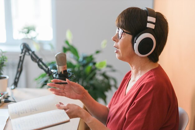 Prezenterka radiowa w średnim wieku rozmawiająca do mikrofonu i czytająca audycję radiową w Internecie