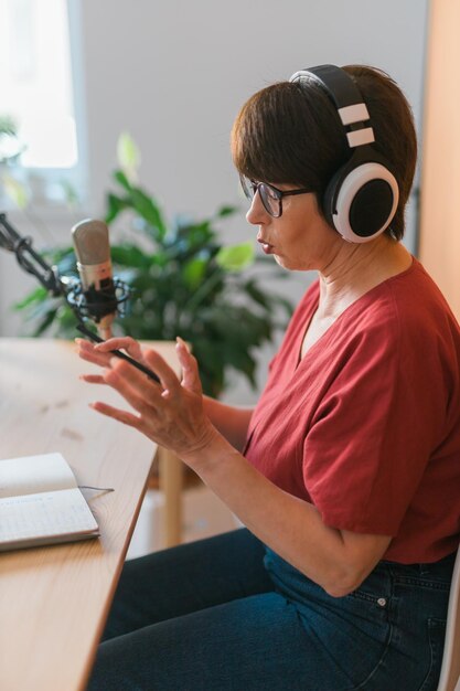 Prezenterka radiowa w średnim wieku rozmawiająca do mikrofonu i czytająca koncepcję transmisji radiowej wiadomości online
