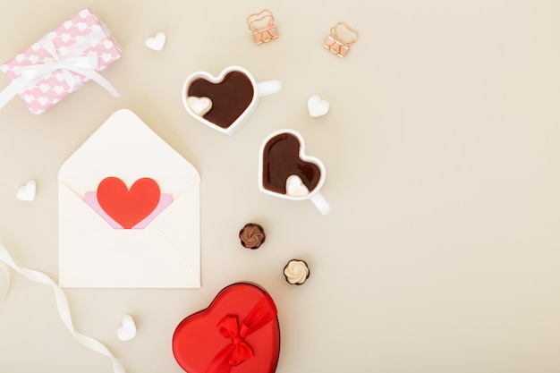 Prezenty koncepcyjne dla bliskich na walentynki dzień kobiet dzień matki lub urodziny Białe koperty wokół prezentów w pudełkach dwie filiżanki kakao w kształcie serca i czekolady
